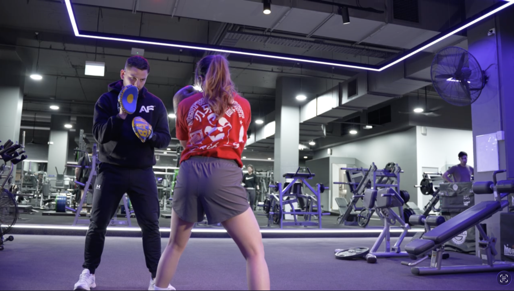 Coach Baki holding focus mitts for a woman during boxing training